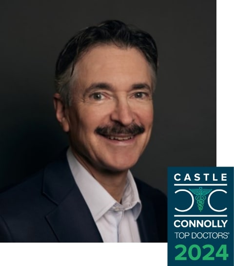 Portrait of a smiling middle-aged man with a mustache, wearing a suit, with a "castle connolly top doctors 2024" badge in the corner.